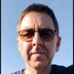 Man wearing glasses outdoors against blue sky