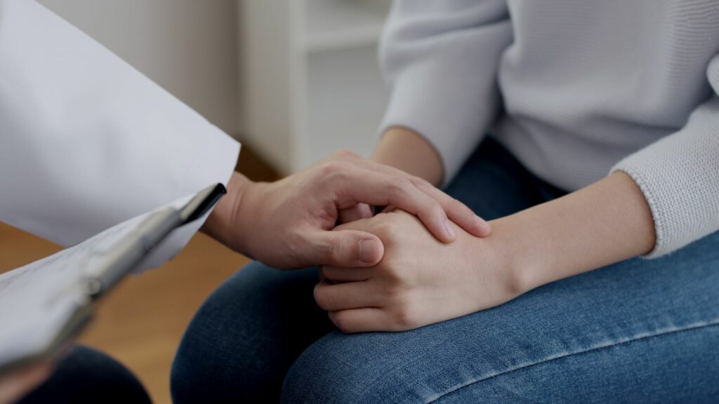 Doctor holding patient's hand during consultation