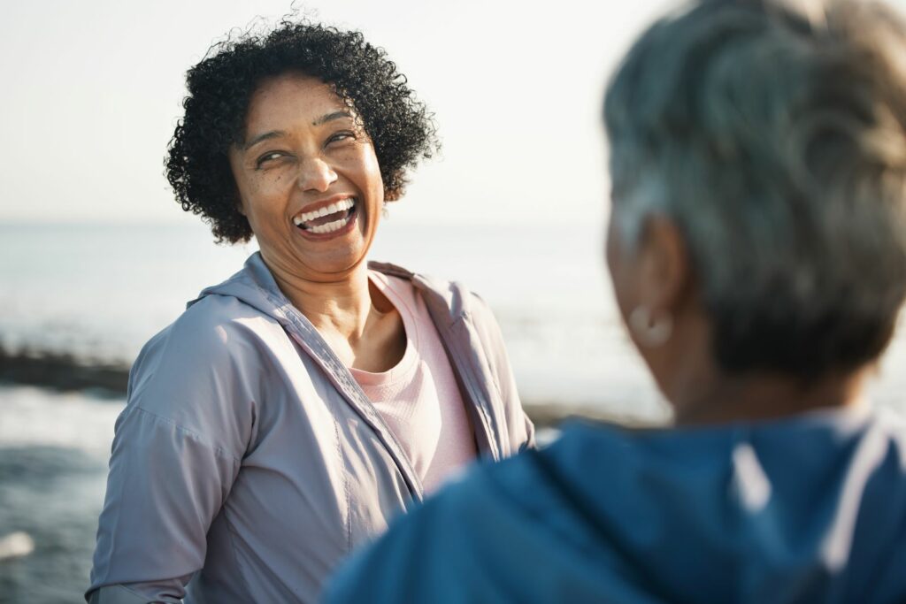 Two women laughing together by the ocean
