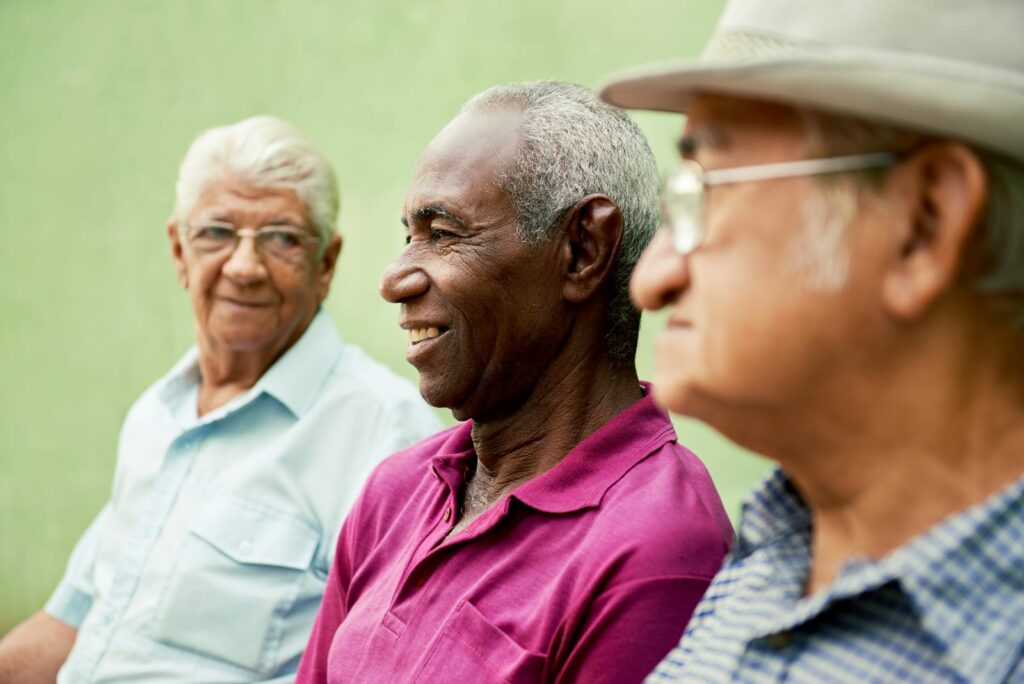 Three elderly men smiling together outdoors