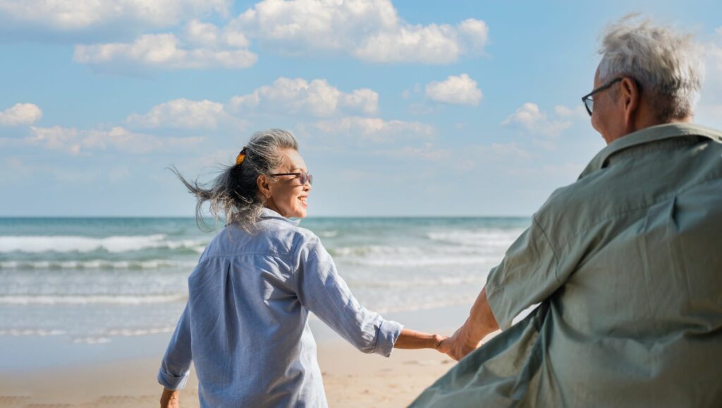Older couple holding hands on a sunny beach