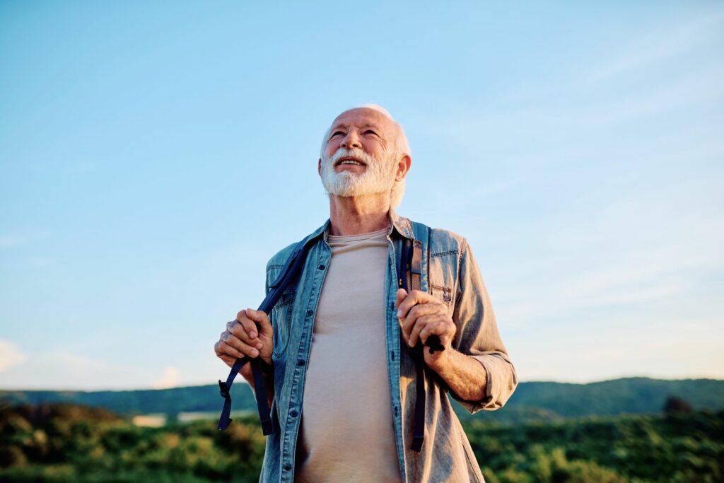 Smiling older man hiking beneath a clear blue sky