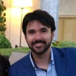 Smiling bearded man in blue blazer indoors