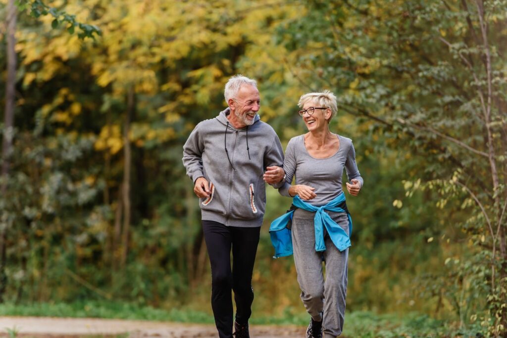 Smiling older couple jogging through an autumn park